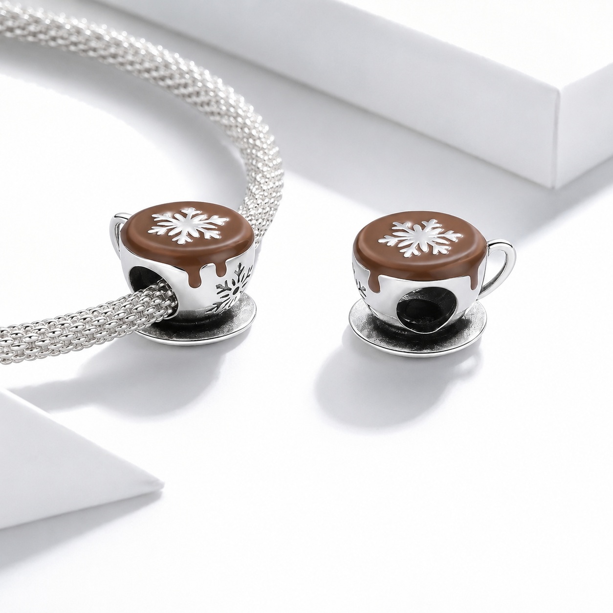 Two coffee-themed earrings with a snowflake design on a white background