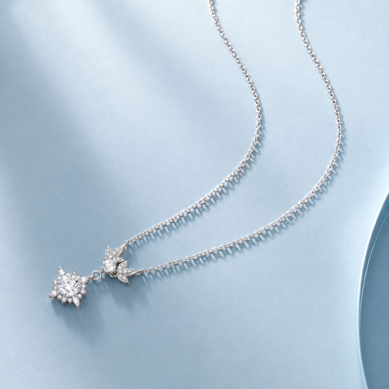 Silver necklace with star-shaped pendants on a light blue background