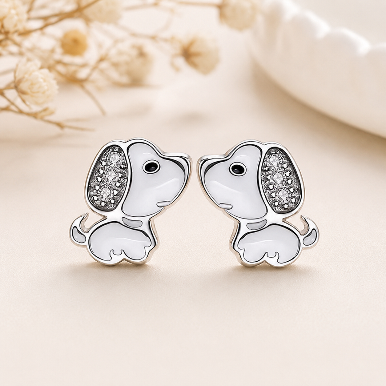 Pair of dog-shaped earrings with sparkling details on a light background