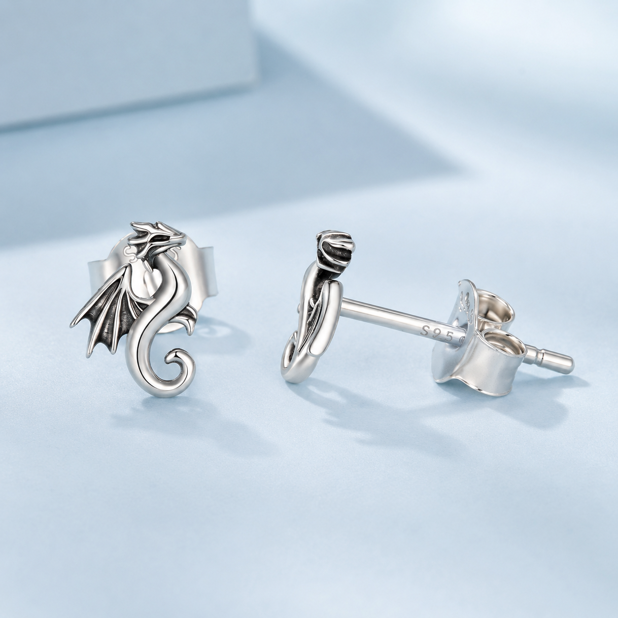 Silver dragon-shaped earrings on a light blue background