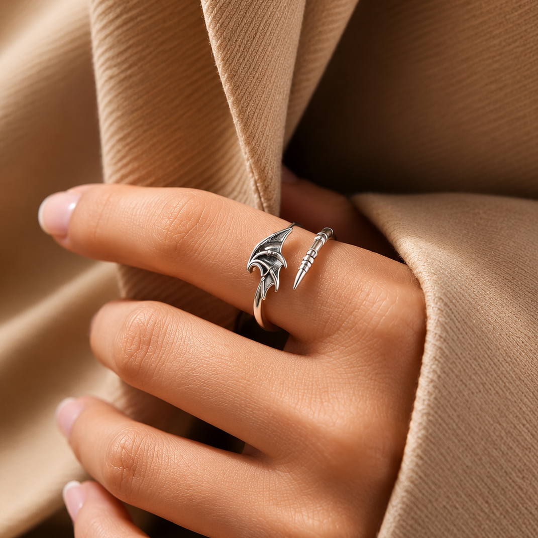 Hand wearing a silver ring with a unique design against a beige fabric background