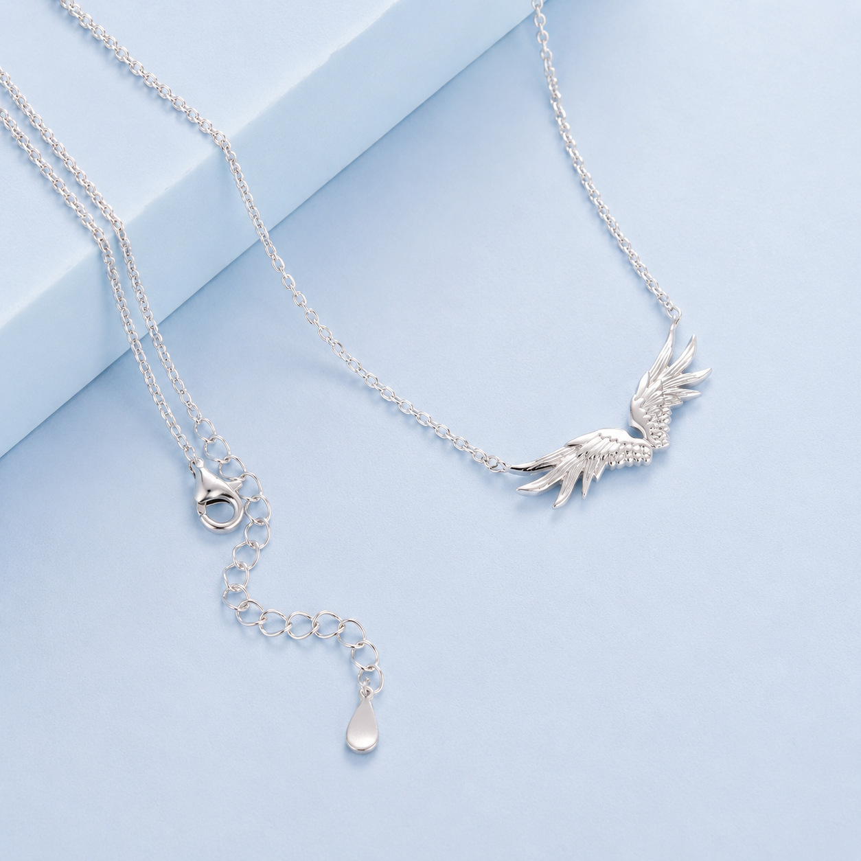 Silver necklace with a leaf design on a light blue background