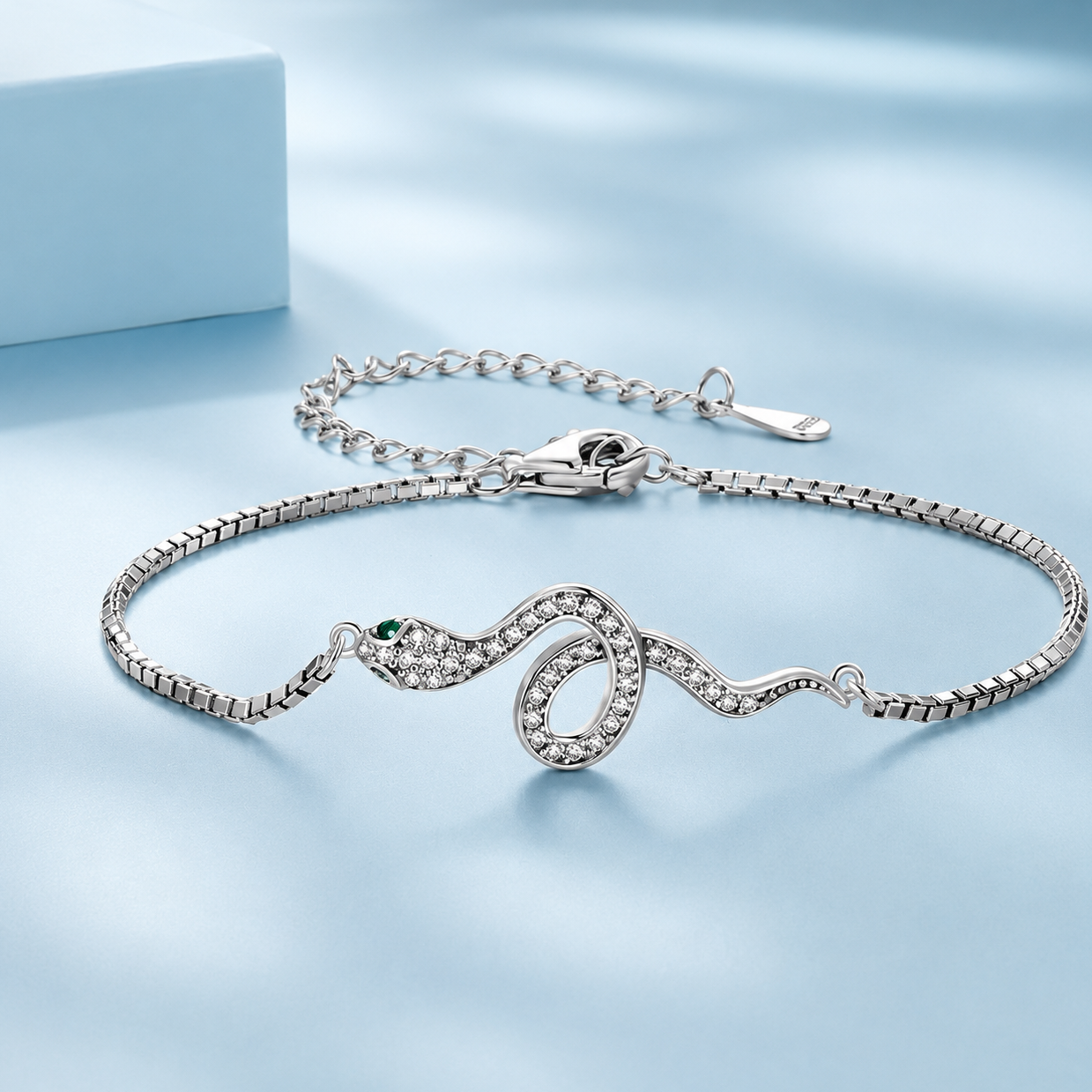 Silver snake bracelet with green gemstone on a light blue background
