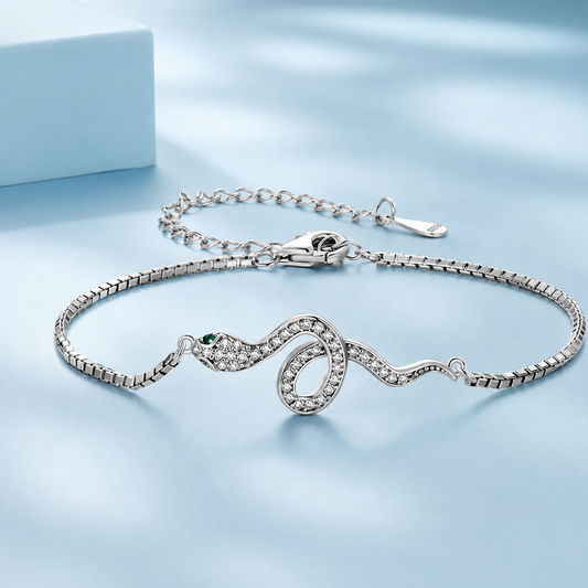 Silver snake bracelet with green gemstone on a light blue background