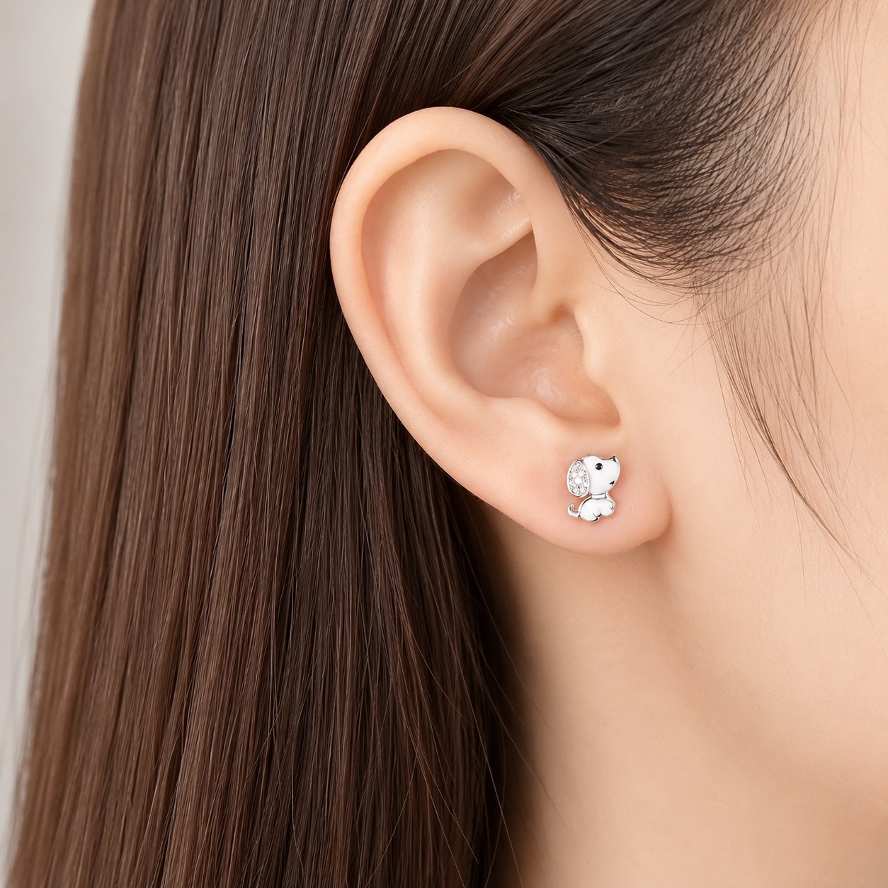 Close-up of an ear wearing a small earring with a neutral background