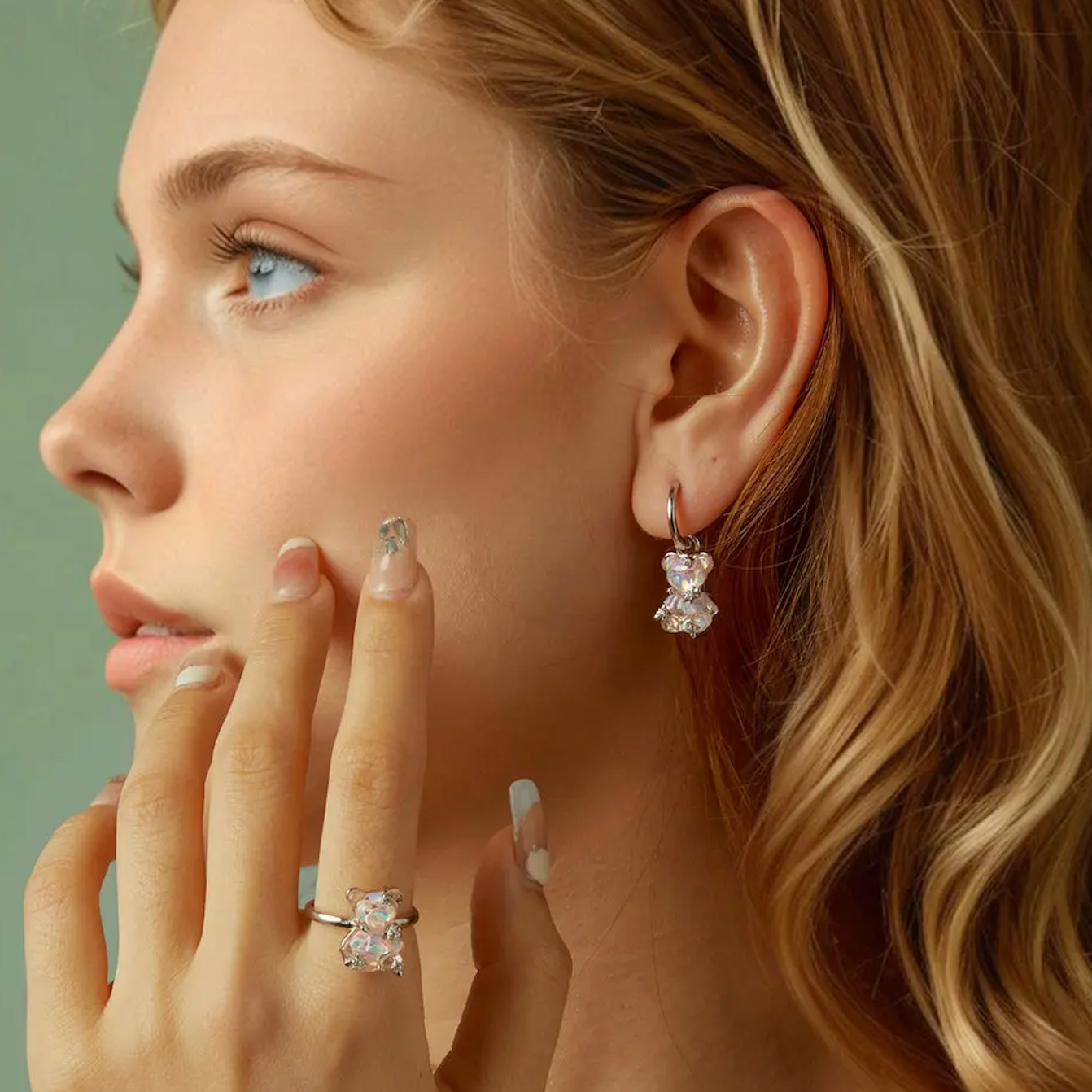 Close-up of a woman wearing diamond earrings and ring against a green background