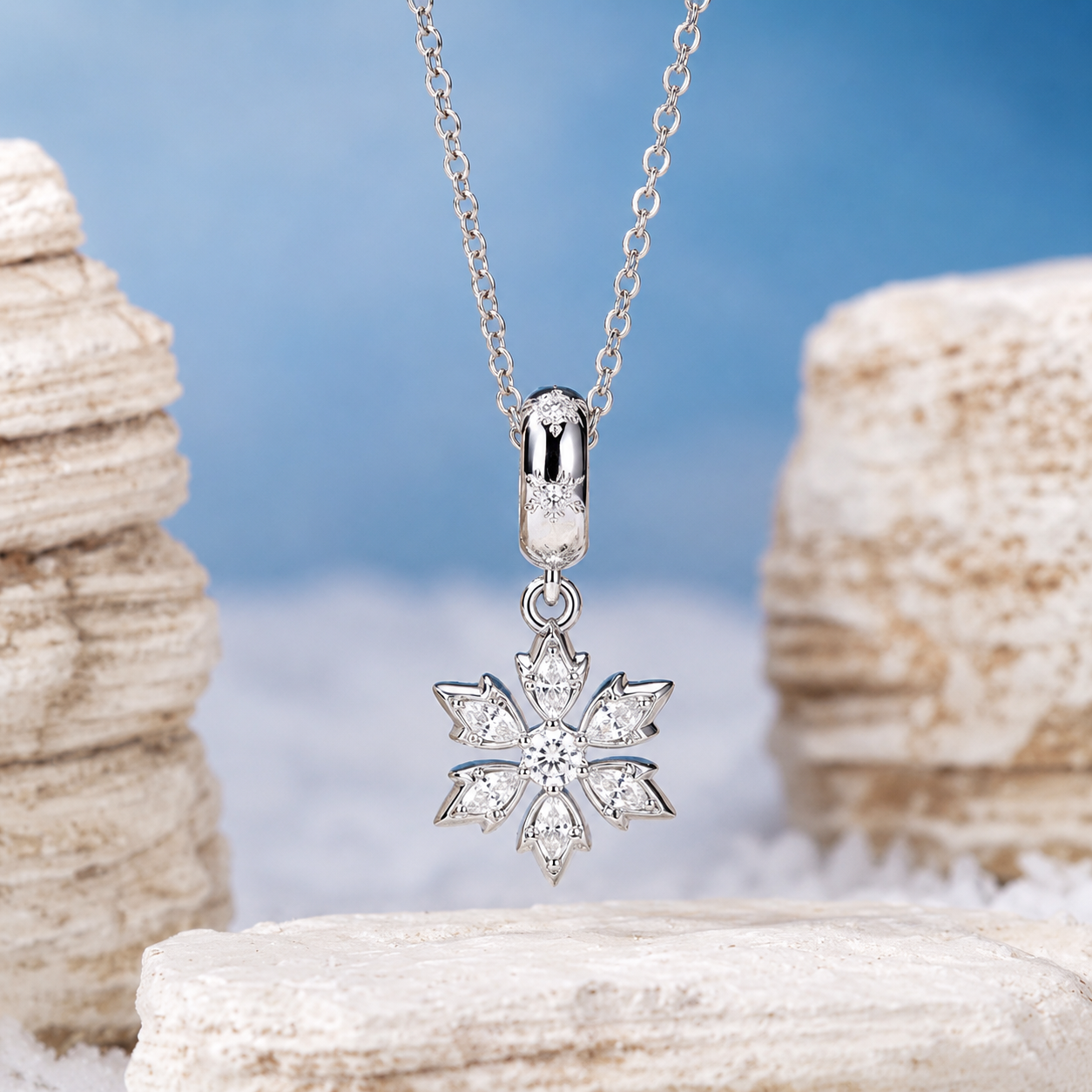 Silver snowflake pendant necklace on a chain against a natural stone background
