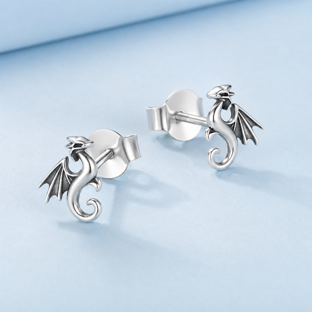 Silver dragon-shaped earrings on a light blue background