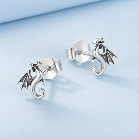 Silver dragon-shaped earrings on a light blue background