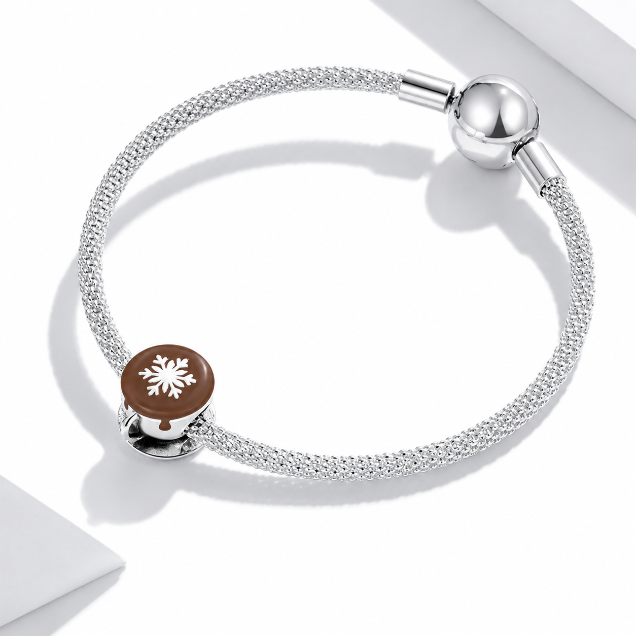 Silver bracelet with a brown charm featuring a snowflake design on a white background