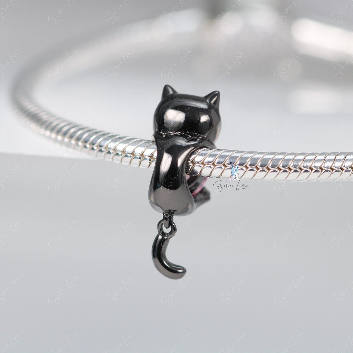 Black cat holding a heart bead charm
