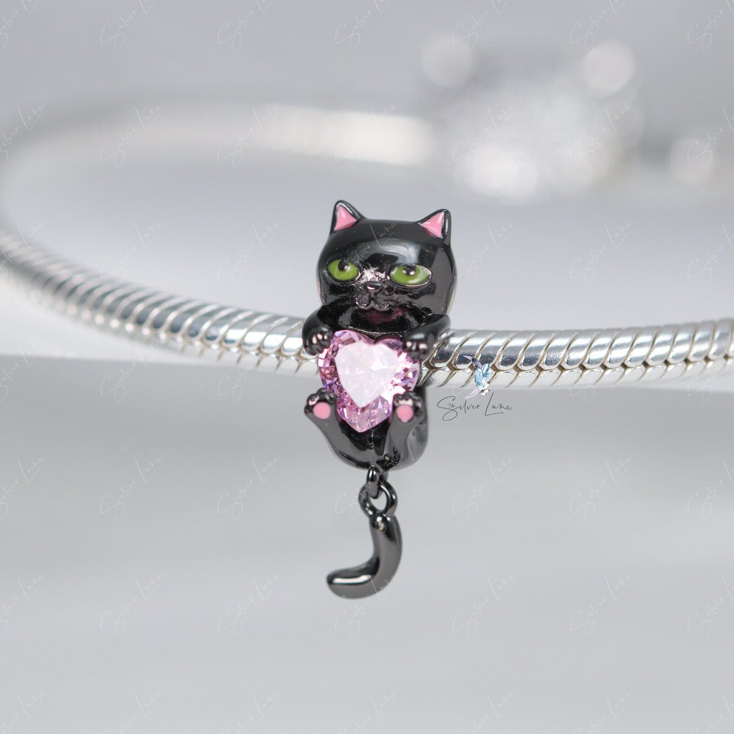 Black cat holding a heart bead charm