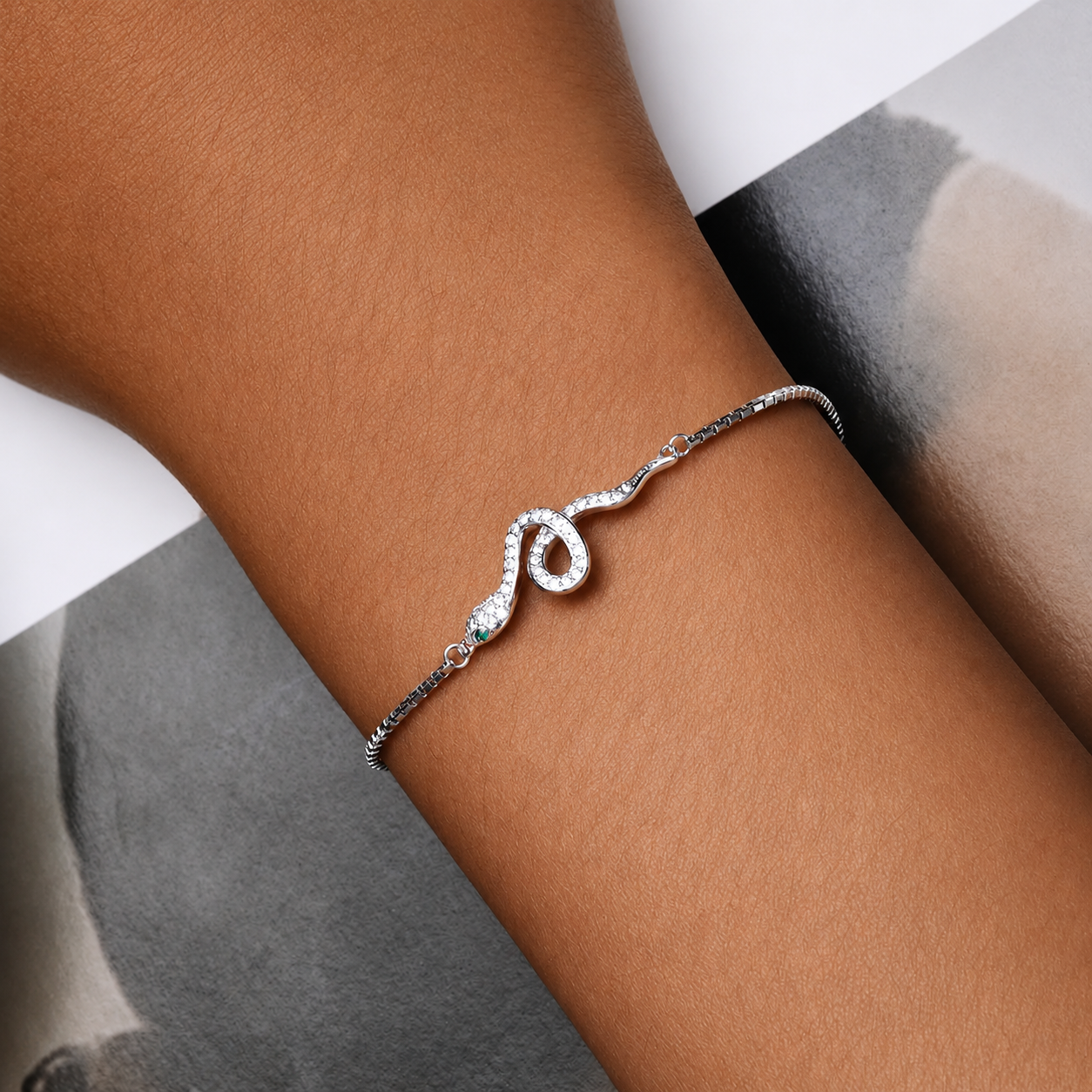 Silver bracelet with a small gemstone on a person's wrist against a neutral background