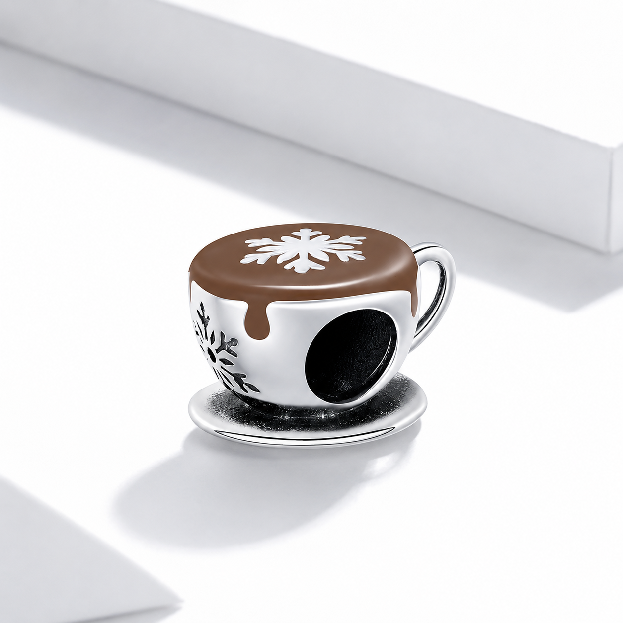 Decorative coffee cup charm with snowflake design on a white background
