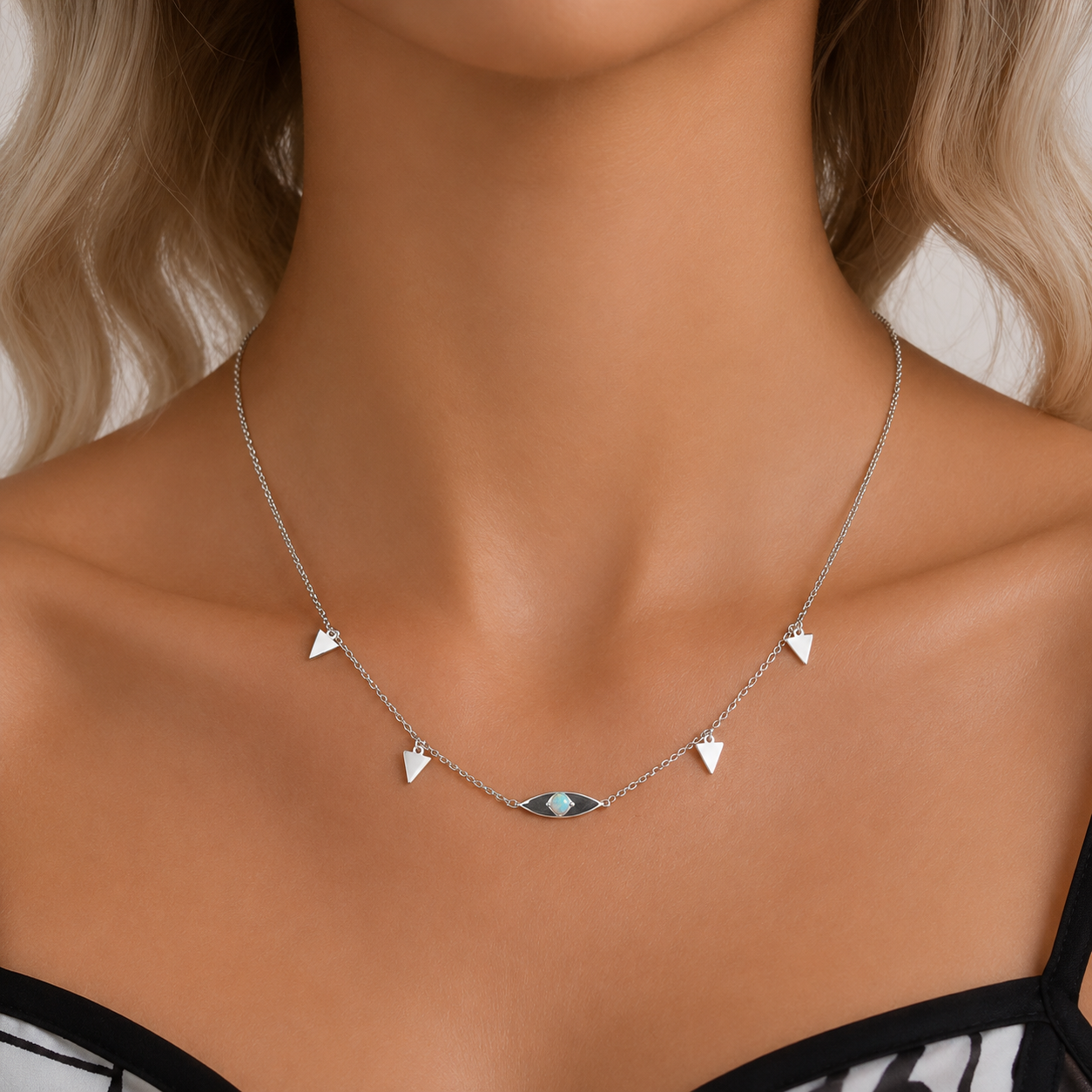A silver-toned delicate necklace with five small triangular charms, including one central marquise-shaped charm, shown on a model's neck.