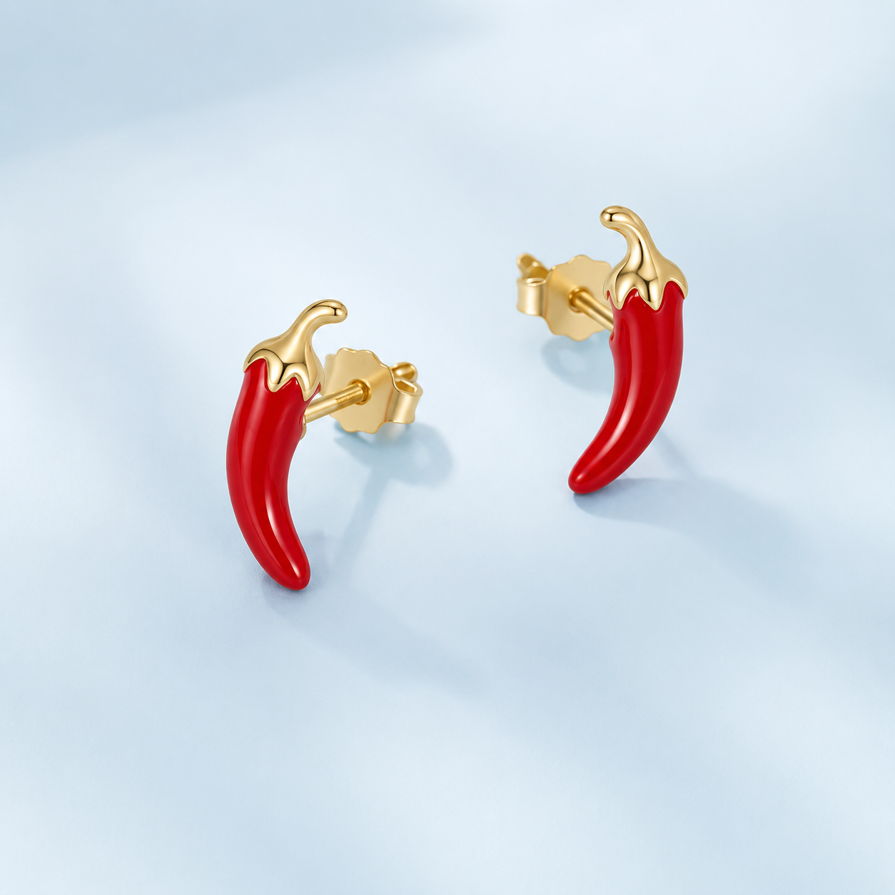 Red chili pepper-shaped earrings with gold posts on a light blue background